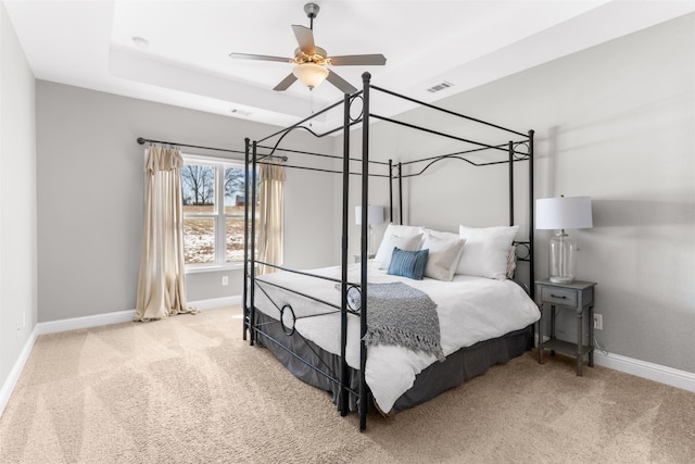 carpeted bedroom featuring ceiling fan and a tray ceiling