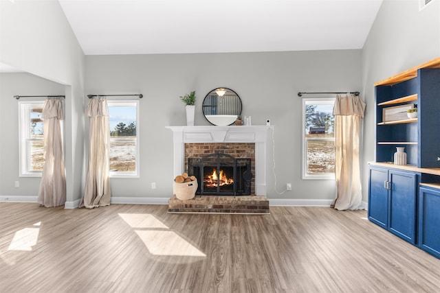 living room with plenty of natural light, a brick fireplace, and light wood-type flooring