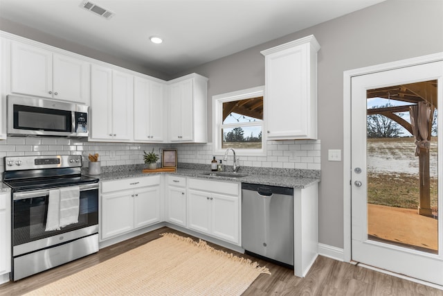 kitchen featuring white cabinetry, sink, decorative backsplash, stainless steel appliances, and light stone countertops