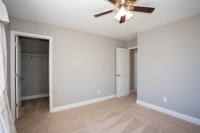 unfurnished bedroom with ceiling fan, a walk in closet, a closet, and light carpet