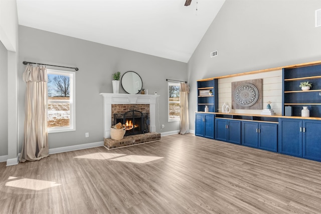 unfurnished living room with high vaulted ceiling, a fireplace, and light hardwood / wood-style floors