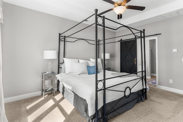 carpeted bedroom with a barn door and ceiling fan