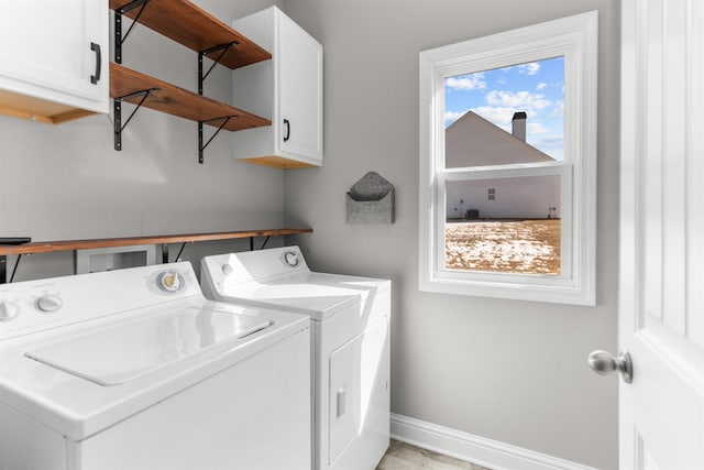 clothes washing area with cabinets and separate washer and dryer