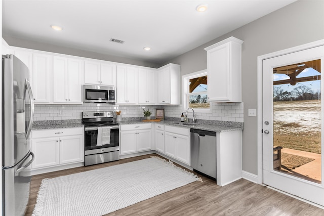 kitchen with white cabinetry, sink, stainless steel appliances, and light stone countertops