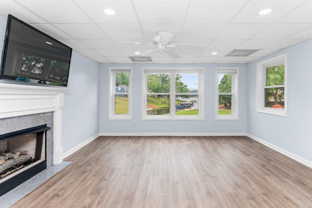 1060 Old Rock Rd, Greensboro, GA 30642 - unfurnished living room featuring a fireplace with flush hearth, ceiling fan, plenty of natural light, wood finished floors, and a paneled ceiling