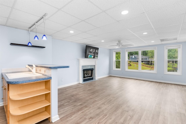 1060 Old Rock Rd, Greensboro, GA 30642 - unfurnished living room featuring a drop ceiling, baseboards, light wood-style flooring, ceiling fan, and a sink