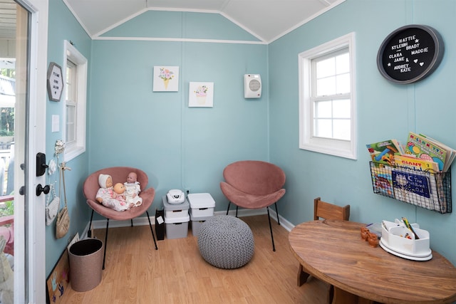 sitting room with wood finished floors, ornamental molding, lofted ceiling, and baseboards