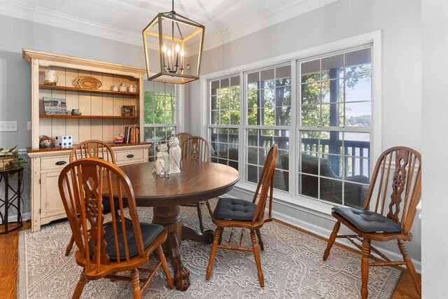 dining space with crown molding, a chandelier, and light wood-style flooring