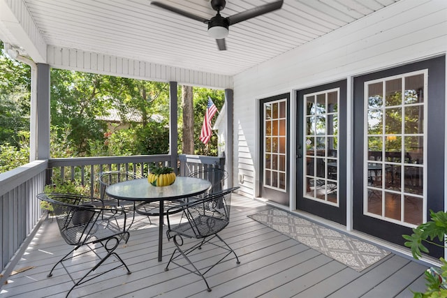 wooden terrace with outdoor dining area and a ceiling fan