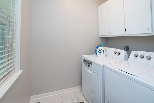 washroom featuring washer and clothes dryer, cabinet space, and baseboards