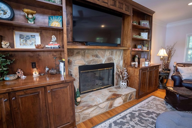 living area with light wood finished floors, crown molding, and a fireplace