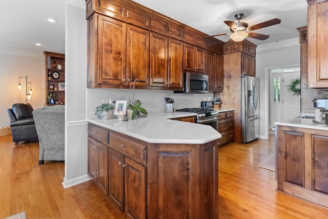 kitchen with appliances with stainless steel finishes, a ceiling fan, crown molding, light wood-type flooring, and backsplash