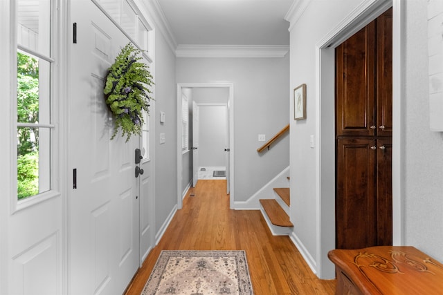 foyer entrance with light wood finished floors, crown molding, plenty of natural light, and stairway