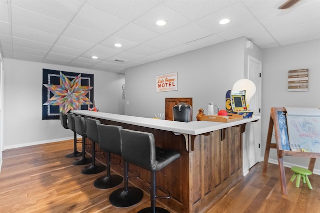 indoor dry bar with wood finished floors, baseboards, recessed lighting, and a paneled ceiling
