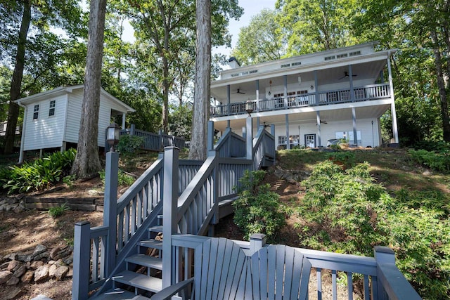 rear view of property with ceiling fan, stairs, and fence