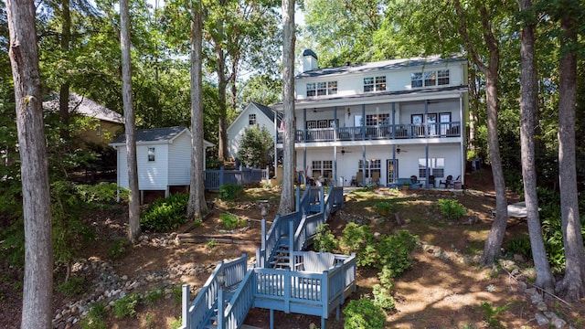 rear view of house featuring stairs, a ceiling fan, an outdoor structure, a chimney, and a storage shed
