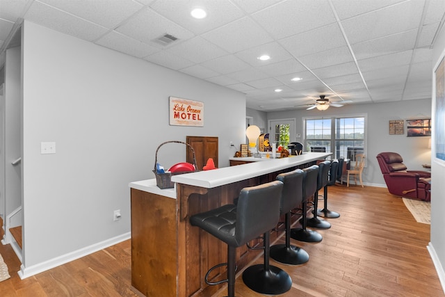 indoor dry bar featuring a paneled ceiling, light wood-style flooring, recessed lighting, baseboards, and ceiling fan
