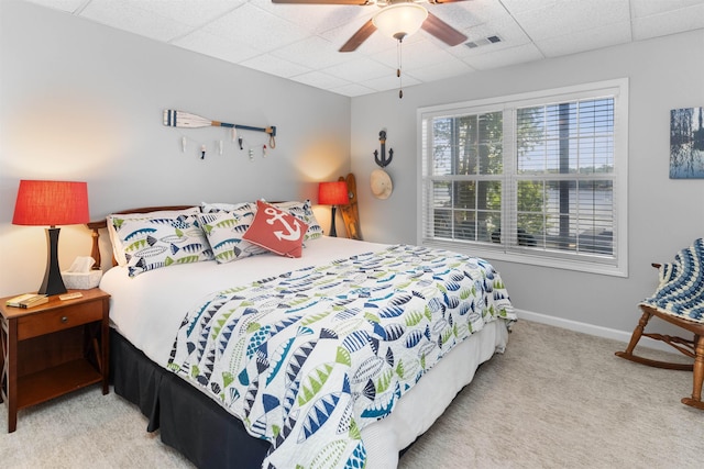 bedroom featuring a drop ceiling, carpet floors, a ceiling fan, and baseboards