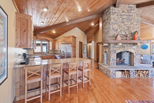 kitchen featuring wood ceiling, stainless steel appliances, light wood-style floors, a fireplace, and a sink