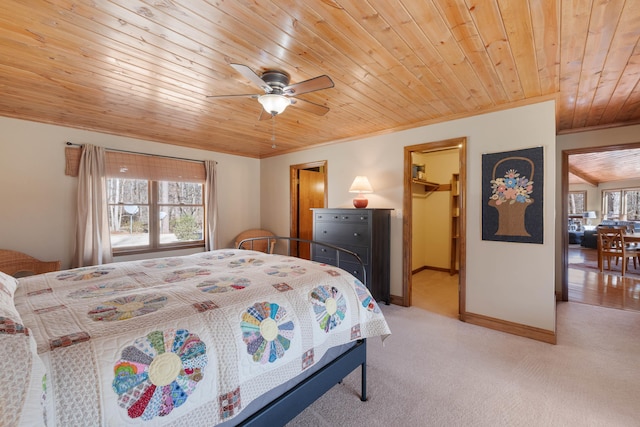 bedroom with a walk in closet, ornamental molding, light carpet, wooden ceiling, and baseboards