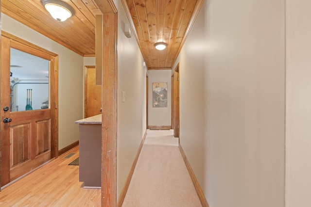 hallway featuring wooden ceiling, visible vents, baseboards, ornamental molding, and light wood-type flooring