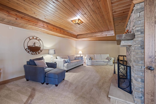 living area featuring baseboards, a raised ceiling, wooden ceiling, a stone fireplace, and carpet floors