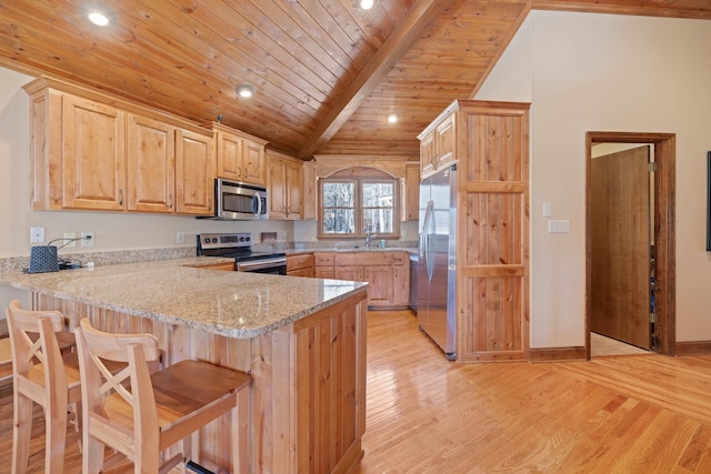 kitchen featuring stainless steel appliances, light brown cabinets, light wood-style floors, and a peninsula
