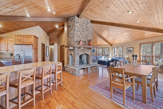 dining room featuring high vaulted ceiling, a stone fireplace, wood ceiling, beam ceiling, and light wood finished floors