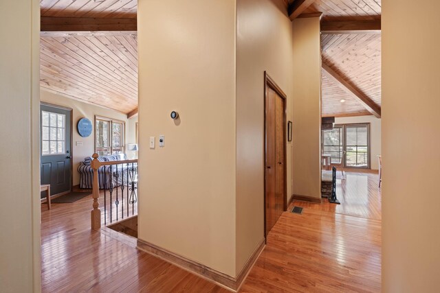 hallway featuring a healthy amount of sunlight, light wood finished floors, wood ceiling, and beam ceiling
