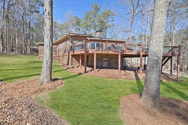 back of house with a chimney, a lawn, and a wooden deck