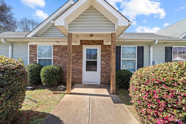 property entrance featuring stone siding and a shingled roof