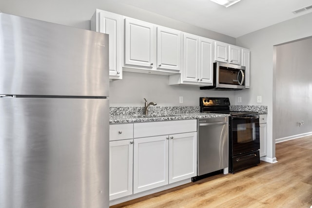 kitchen featuring visible vents, a sink, stainless steel appliances, light wood-style floors, and white cabinets