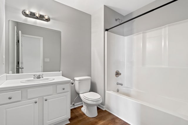 bathroom featuring vanity, wood finished floors, baseboards, shower / tub combination, and toilet