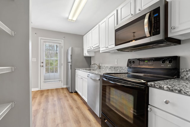 kitchen with light wood-type flooring, a sink, stainless steel appliances, white cabinets, and light stone countertops