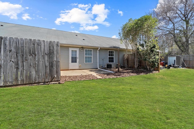 rear view of property featuring a lawn, a fenced backyard, and a shed