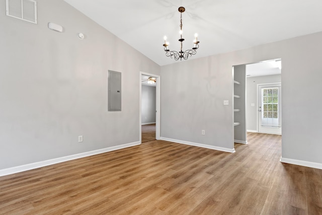 empty room featuring visible vents, light wood-type flooring, vaulted ceiling, electric panel, and ceiling fan with notable chandelier