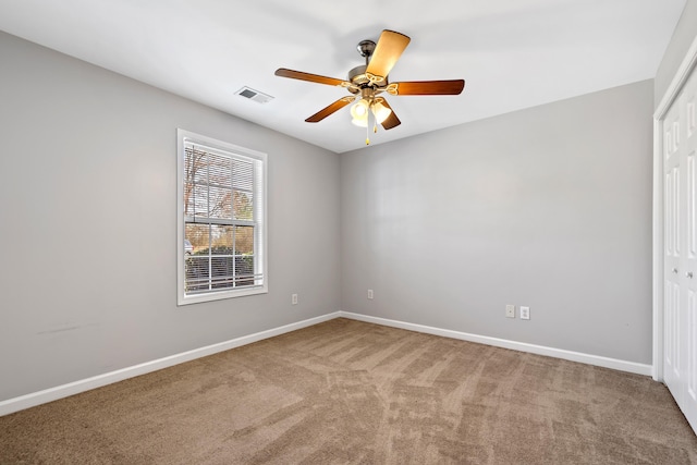 carpeted spare room featuring visible vents, ceiling fan, and baseboards