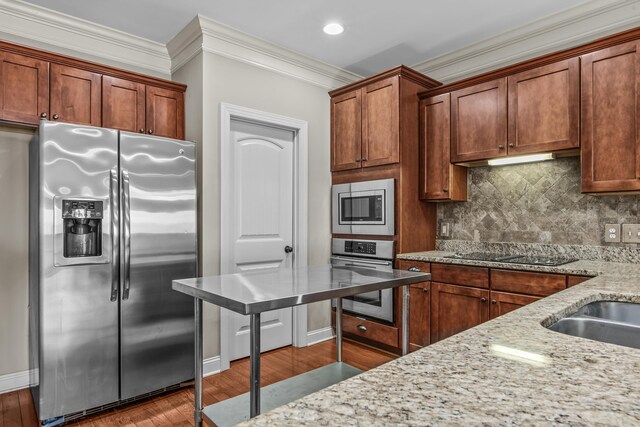 kitchen with light stone countertops, appliances with stainless steel finishes, and light hardwood / wood-style floors