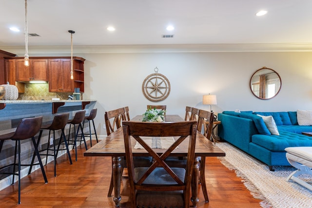 dining area with crown molding and dark wood-type flooring