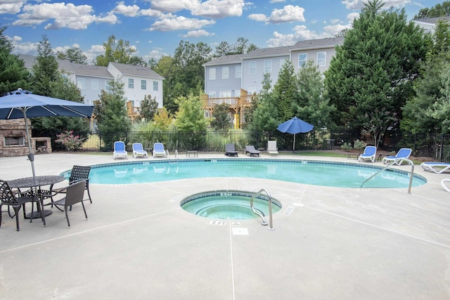 view of swimming pool featuring a hot tub, a patio, and an outdoor stone fireplace