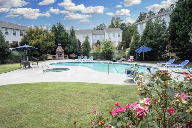 view of swimming pool featuring a fireplace, a patio area, a lawn, and a hot tub