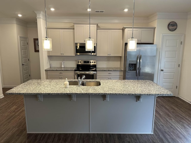 kitchen with a breakfast bar, dark wood-style flooring, a sink, appliances with stainless steel finishes, and an island with sink