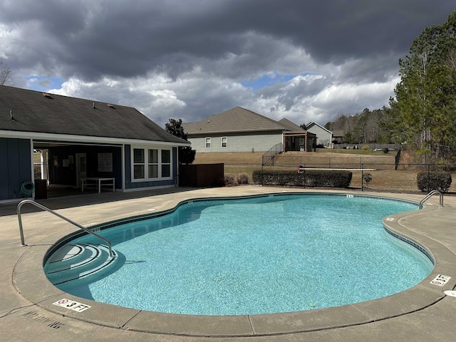 community pool with a patio and fence