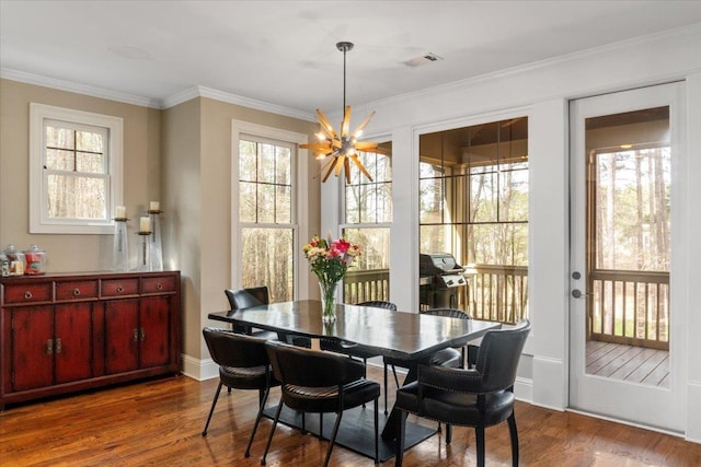 dining space featuring baseboards, visible vents, wood finished floors, crown molding, and a notable chandelier