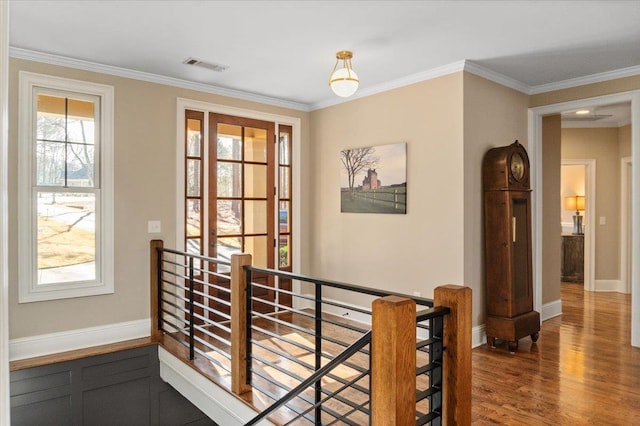 hallway featuring visible vents, wood finished floors, an upstairs landing, and crown molding