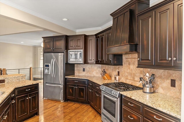 kitchen featuring light wood-style floors, premium range hood, light stone counters, and stainless steel appliances