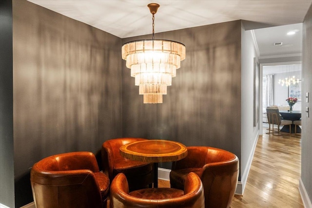 dining space with a chandelier, ornamental molding, wood finished floors, and baseboards