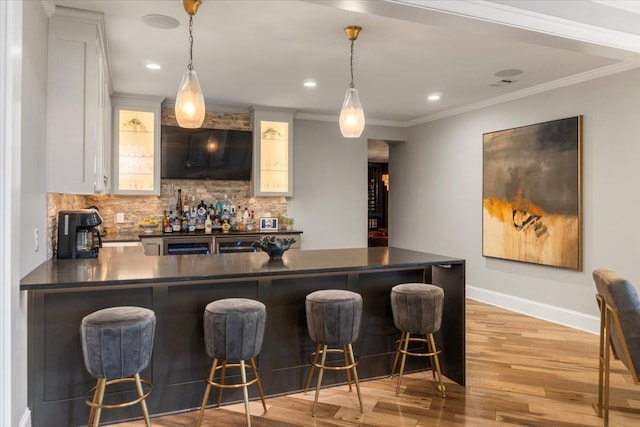 bar featuring ornamental molding, light wood finished floors, indoor bar, and backsplash