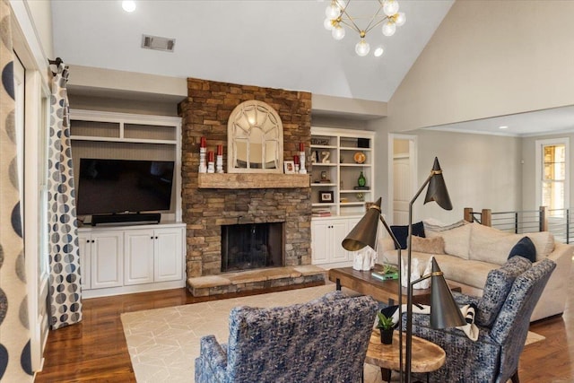 living area featuring visible vents, built in features, wood finished floors, a fireplace, and a chandelier