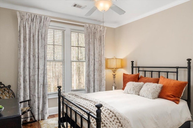 bedroom with wood finished floors, visible vents, baseboards, a ceiling fan, and ornamental molding